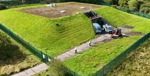 An aerial photo shows men in PPE and two vans at Stanley Hollowhouse following the installation of the cement-free, basalt-reinforced base for Scottish Water’s first verified Net Zero site.