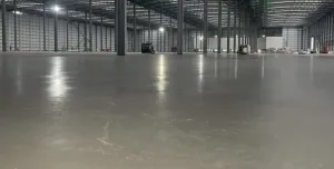 A large, newly poured concrete floor inside a large warehouse