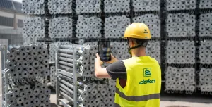 A man in Doka branded PPE uses an AI device to count formwork elements