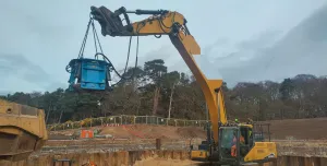 A yellow excavator lifts a blue pile cropper at the Port of Nigg, Scotland