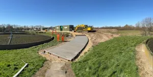A waste water treatment plant with a CoMLaG mix access road in the foreground surrounded by grassy banks