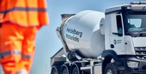 A man in orange PPE walks past a Heidelberg Materials-branded cement mixer