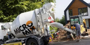 Two men unload concrete from one of Micromix’s agile trucks, which can deliver concrete loads from 0.5 to 4 m³, now with added convenience via online ordering.