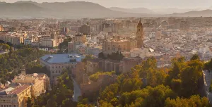 A panoramic photo of Malaga city centre with mountains in the distance, with the bullring lower right and a large church middle left.