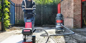 A man with beard using one of Trelawny’s new VoltMax range, which includes a grinder, scarifier and stripper – all powered by 82V lithium-ion batteries, prepares a surface for construction work