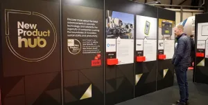 A man stands right of frame looking at entries to the UK Concrete Show's New Product Hub, which are displayed on a large, floor standing board.
