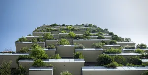 Looking up at the exterior of a high-rise building which features balconies covered in plants