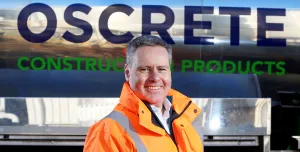 Oscrete director Scott Wilson stand in front of an Oscrete sign wearing orange PPE
