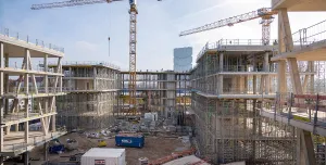 An under construction mid-rise building with two tower cranes in the background