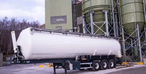 A white, material tanker standing in front of Material Evolution’s Mevo A1 Production Facility in Llay, Wrexham – the UK’s largest producer of ultra-low carbon cement, with a capacity of 120,000 tonnes per year.