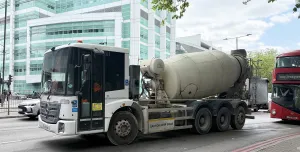A concrete mixer drives along a street in London with a red double decker following 