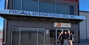 Three men stand awith hands on each other's shoulders outside a two storey, ProAll branded building