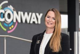A woman standing in front of FM Conway's logo