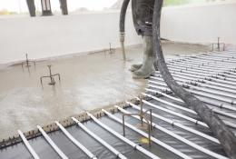 Concrete being poured inside a building over an underfloor heating system
