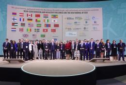 Lots of people standing on a podium with their countries flags in the background following the launch of the UAE and Canada's Breakthrough Initiative at COp28