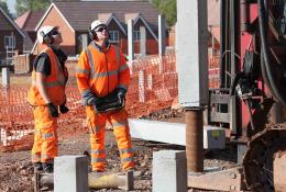 Two men installing concrete piles