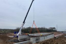 A crane lifting concrete beams to construct a road bridge