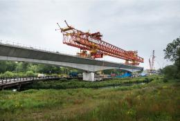 A picture of an orange launching girder sitting on top of an under construction railway viaduct