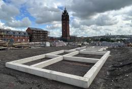 Concrete beams laid on the ground outside with a church tower in the background