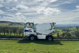 A white mobile concrete mixer in a green field
