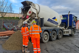Two men in orange PPE in front of a concrete ready mix truck