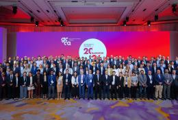 A large group of people standing infront of a white round sign and red lighting