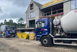 Two blue and grey concrete mixer trucks outside a new build house