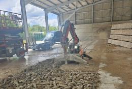 A demolition robot using a hammer to break a concrete floor