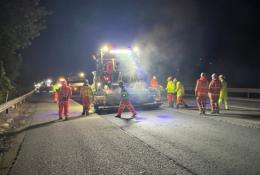 People in PPE repair a road at night