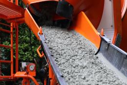 A close up of an orange cement mixer's chute discharging concrete