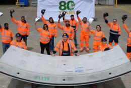 A group of people in orange PPE waving while standing next to a precast concrete tunnel segment