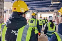 A group of people in PPE walking away from the viewer inside an under construction office building