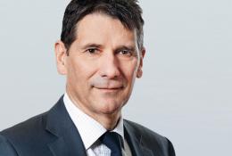 A head and shoulders picture of a man in a dark suit and tie