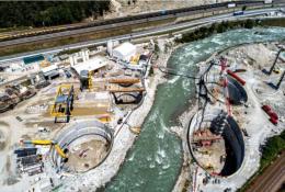 A large construction site divided by a bend in a river