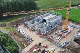 Aerial view of an under construction waste water treatment works with a yellow tower crane