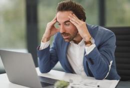 Stressed man working on a laptop in office. A businessman appears stressed and overworked in front of his laptop