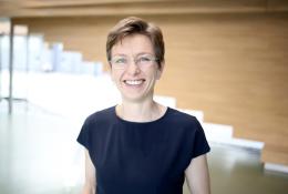 A head and shoulders photo of a woman with short hair, glasses and wearing a black tshirt