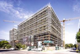 An under construction mid-rise building covered in scaffolding