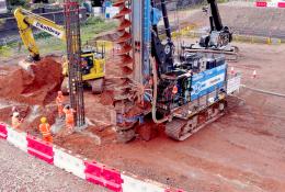 A blue piling rig and a yellow excavator at work on a construction site