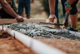 Men spreading wet concrete in a mesh mould