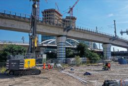 A yellow piling rig stands in front of a bridge on a construction site in Germany