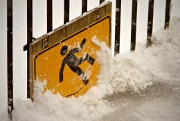 A health and safety sign of a person slipping on ice, covered in snow