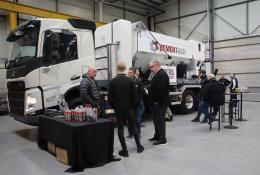 A group of men socialize in front of a volumetric concrete mixer at Volumetric's first Christmas open day was held at its new facility in Wednesbury, in the West Midlands. 