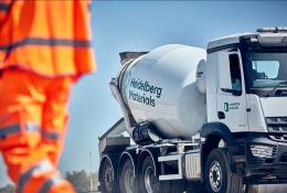 A man in orange PPE and a Heidelberg Materials concrete truck mixer