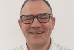 Head and shoulders picture of a smiling man in glasses