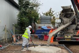 Workers at a construction site spread concrete being discharged by a mobile concrete mixer