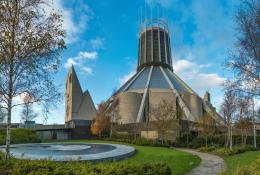 A view of Liverpool Metropolitan Cathedral in early summer with trees and a pond