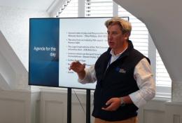 Mike Phillips, CEO British Aggregates Association, wearing a black, fleece gillet, open-necked white shirt and brown chinos, stands in front of a screen, speaking at the BAAs recent Landfill Tax consultation conference.