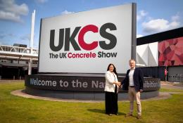 Richard Bradbury (right), Managing Director of The QMJ Group with Helaena Ackers, Exhibition Sales Account Manager, The NEC shake hands outside the NEC in front of a huge UK Concrete Show sign, following the signing of a two-year deal that sees the flagship trade show to stay at Birmingham’s NEC through 2027, with free parking and expanded plans for 2026 edition