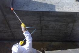 A man in white PPE Waterproofing underground sections of concrete with Vetrofluid using a low pressure pump.